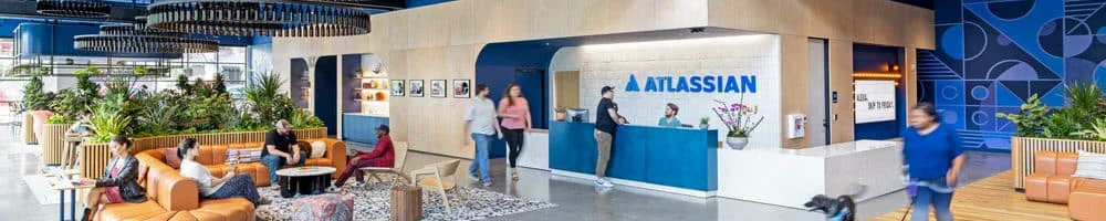 An Atlassian office reception, with blue walls, orange sofas and the Atlassian sign
